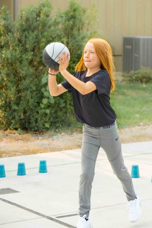 Girl holding a basketball with plastic cups on the ground