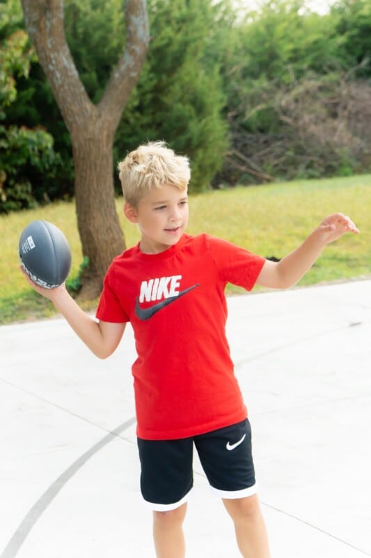 Kid in a red Nike shirt throwing a football