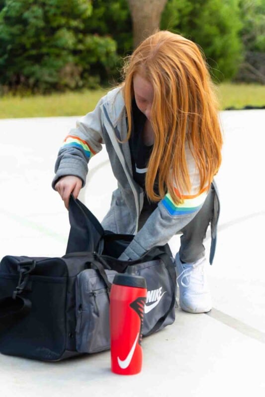 Girl grabbing sports equiptment out of a Nike bag