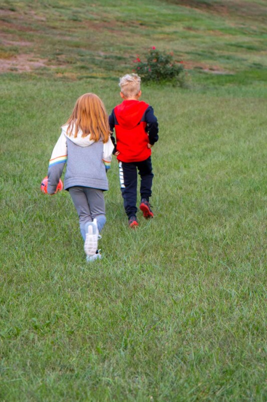 Two kid walking in a field