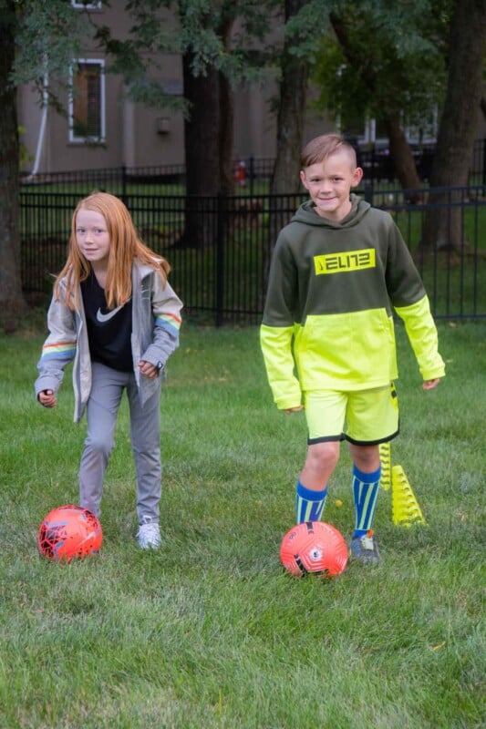 Two kids with pink soccer balls on a grassy field