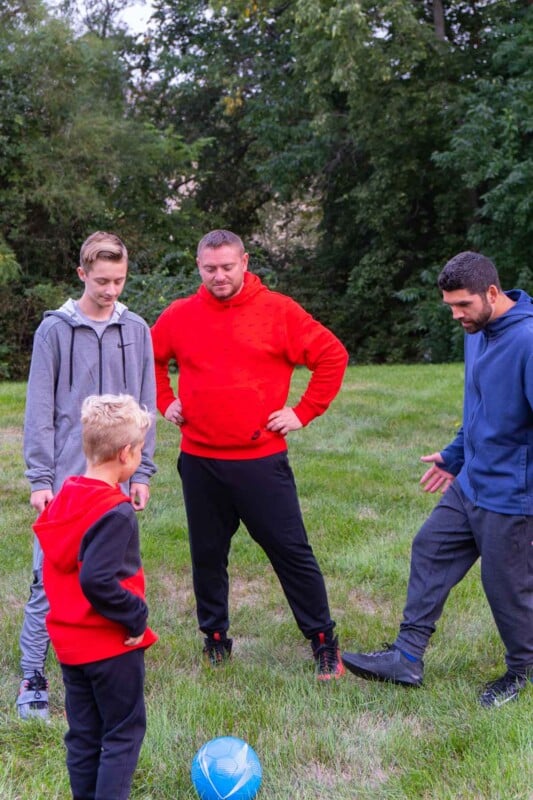 Kid standing with two adults and a teen boy