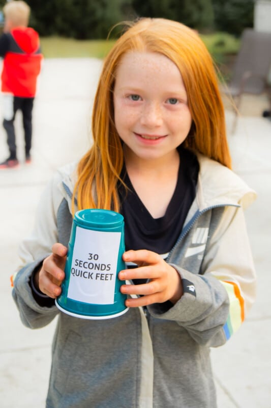 Girl holding a plastic cup that says quick feet