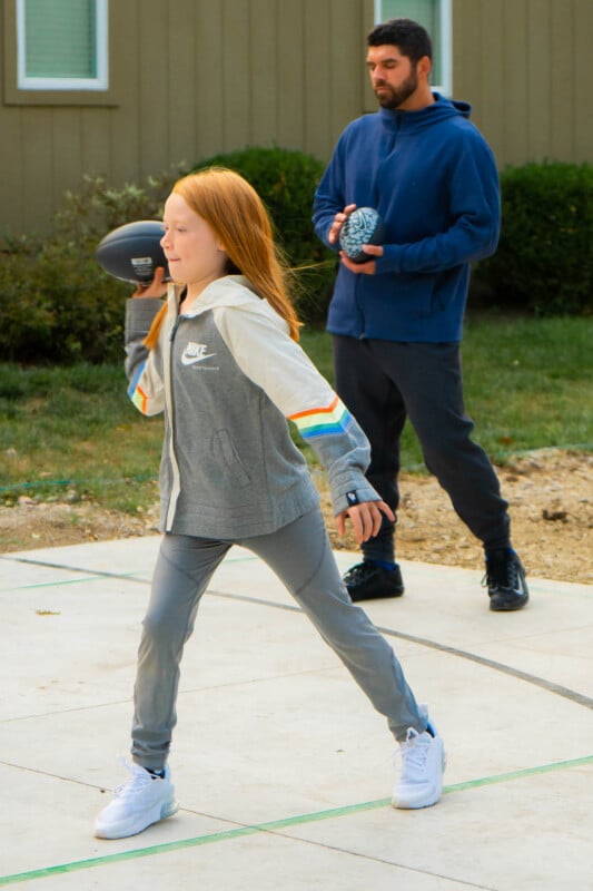 Girl throwing a Nike football in gray clothes