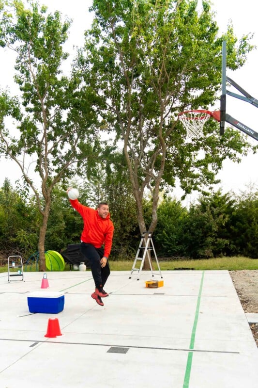 Adult in a red sweatshirt slam dunking