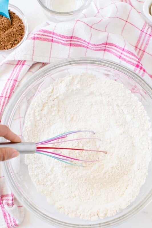 Glass bowl with dry baking ingredients and a pink whisk