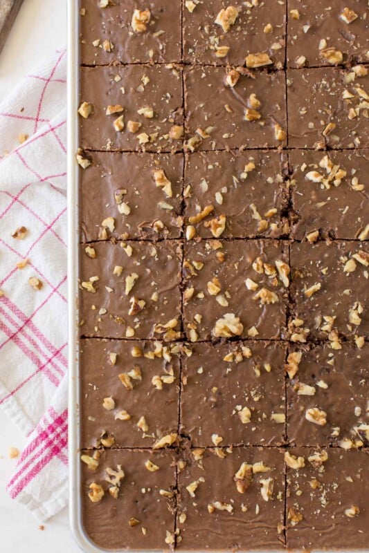 A sheet pan with cut chocolate brownie cake with walnuts