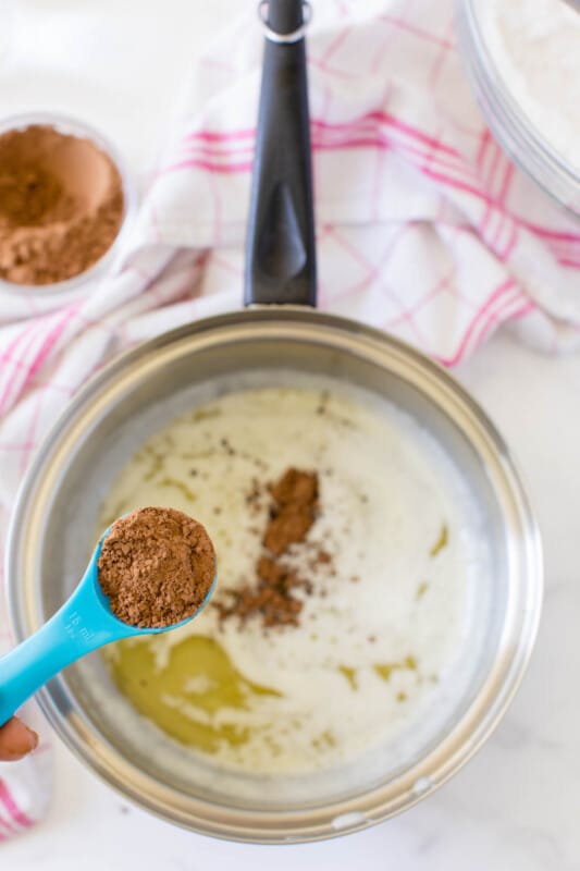 Melted butter in a pot with a spoon of cocoa above it