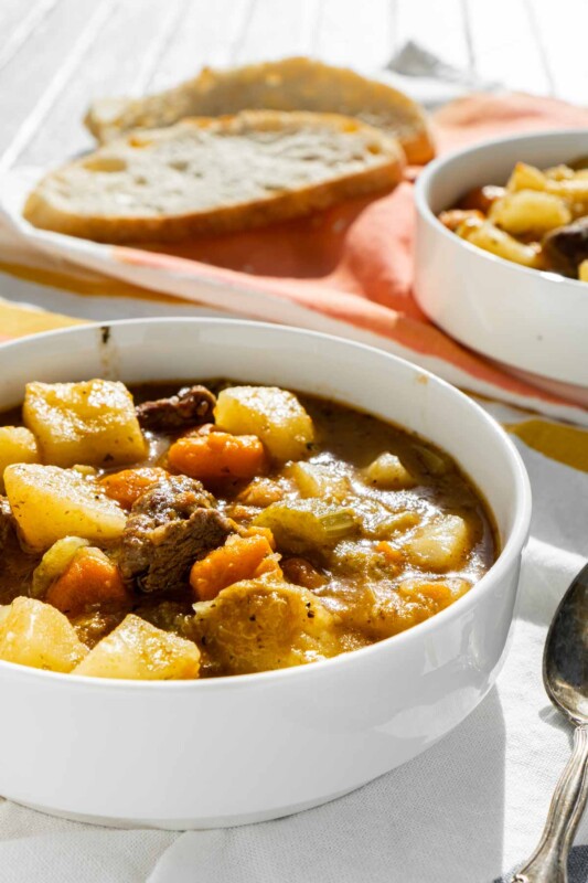 A white bowl with beef stew with potatoes and carrots