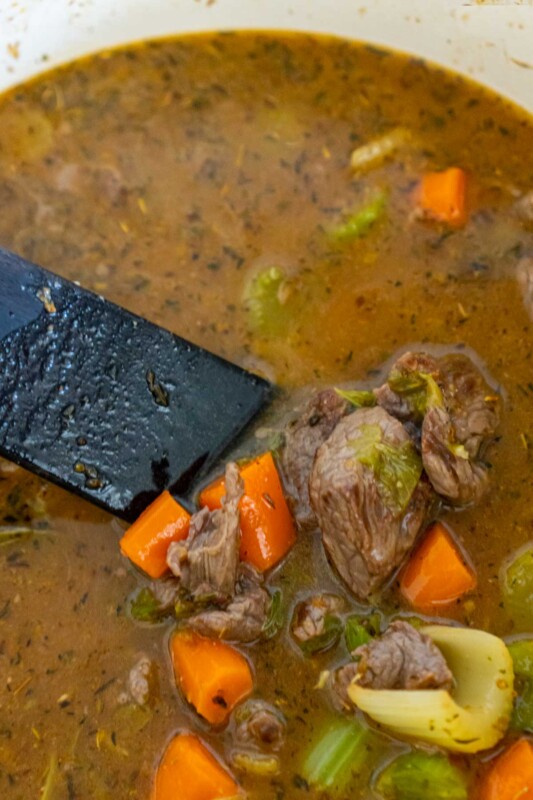 Spatula showing beef and veggies in a beef stew broth