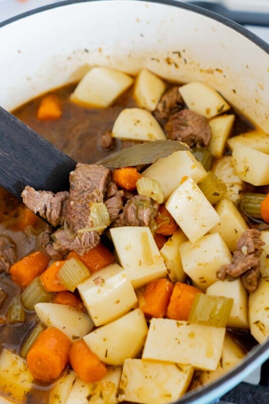 Adding potatoes into a pot of beef stew