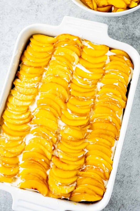 Peach cake topped with fresh peaches in a white rectangle dish