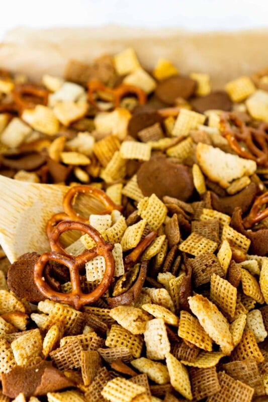 Wooden spoon stirring a batch of homemade Chex Mix