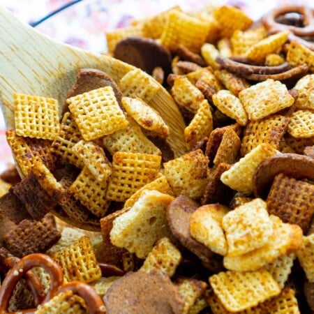 Wooden spoon stirring a batch of homemade Chex Mix