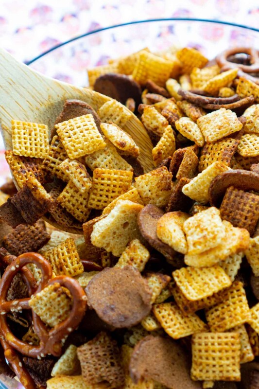 Wooden spoon in a large bowl of homemade Chex Mix