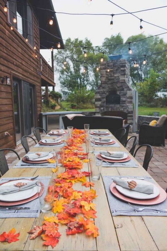 A large table with fall place settings in an outdoor entertaining area
