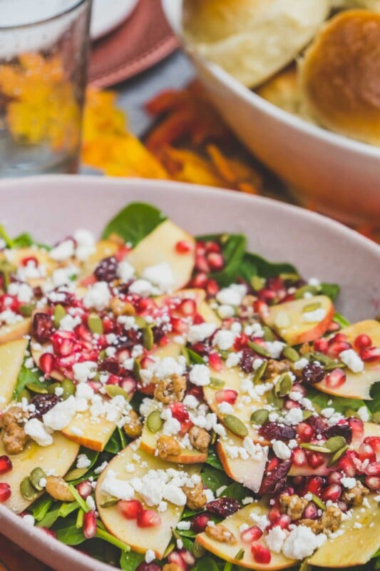 Fall harvest salad with basket of rolls in the background