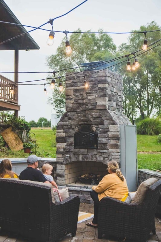 People sitting on chairs in front of a brick oven