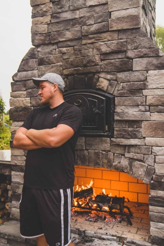 Man standing by fireplace with fire