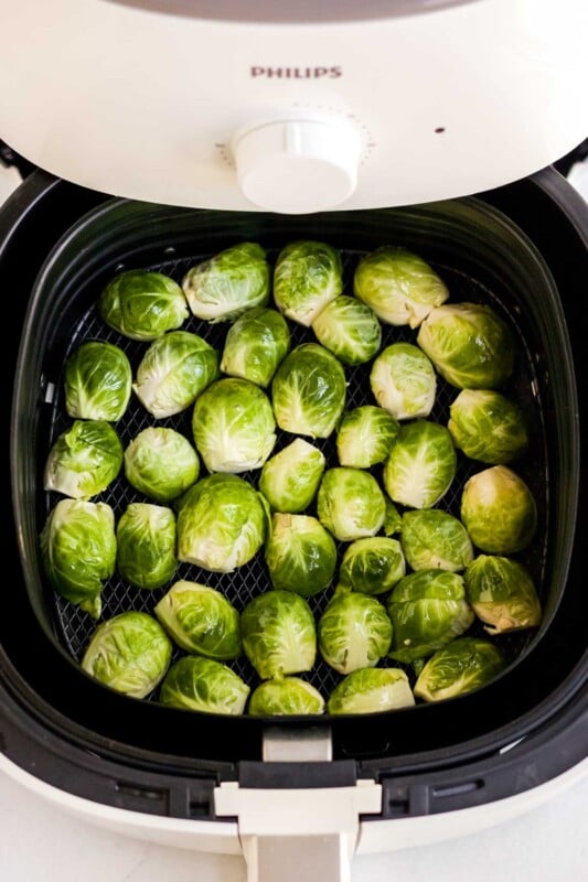 Uncooked brussels sprouts in an air fryer drawer
