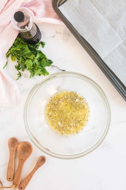 A bowl with butter and spices and parsley on the side