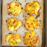 A tray of smashed potatoes on a piece of parchment paper