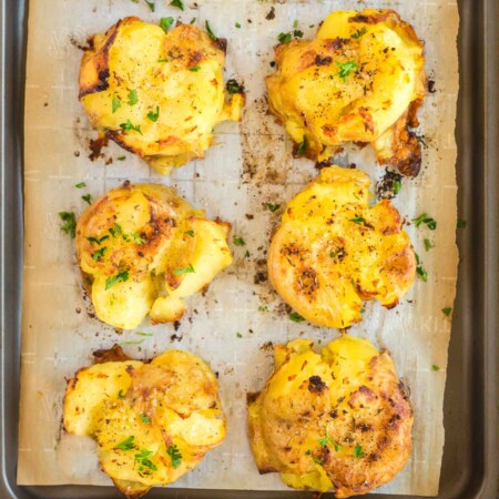 A tray of smashed potatoes on a piece of parchment paper