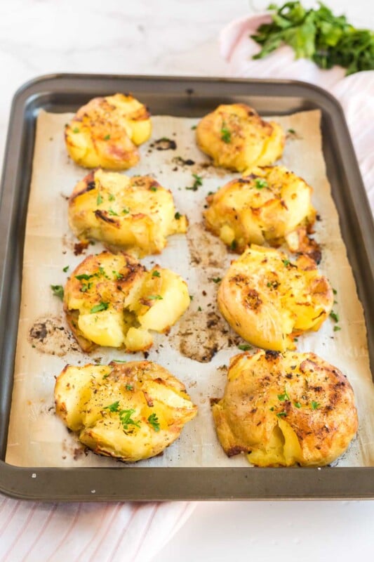 A tray of smashed potatoes on a piece of parchment paper