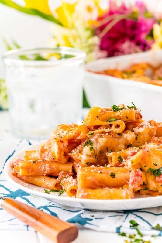 Plate full of baked ziti with a pan of baked ziti in the background