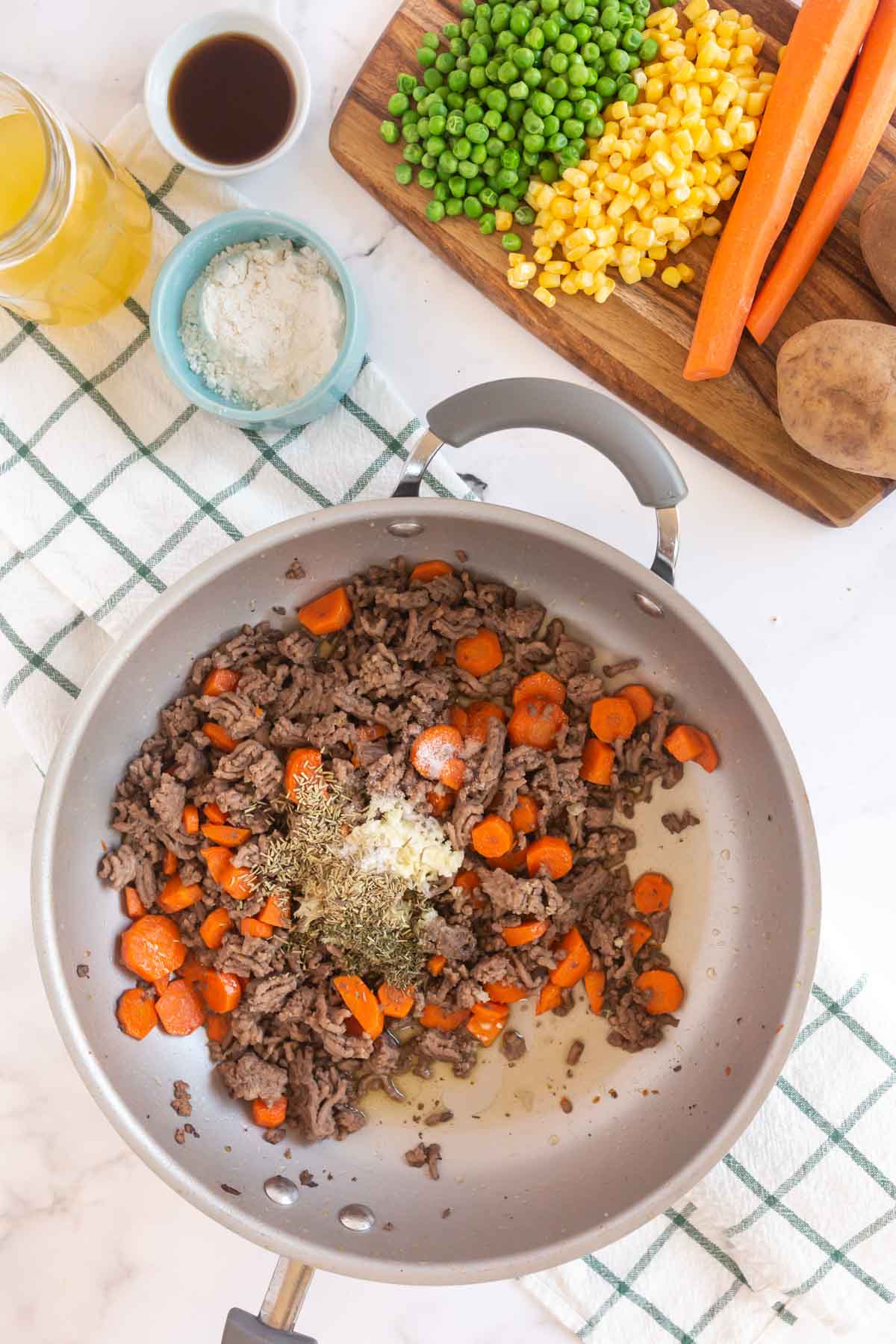 Spices, ground beef, and carrot in a metal pan