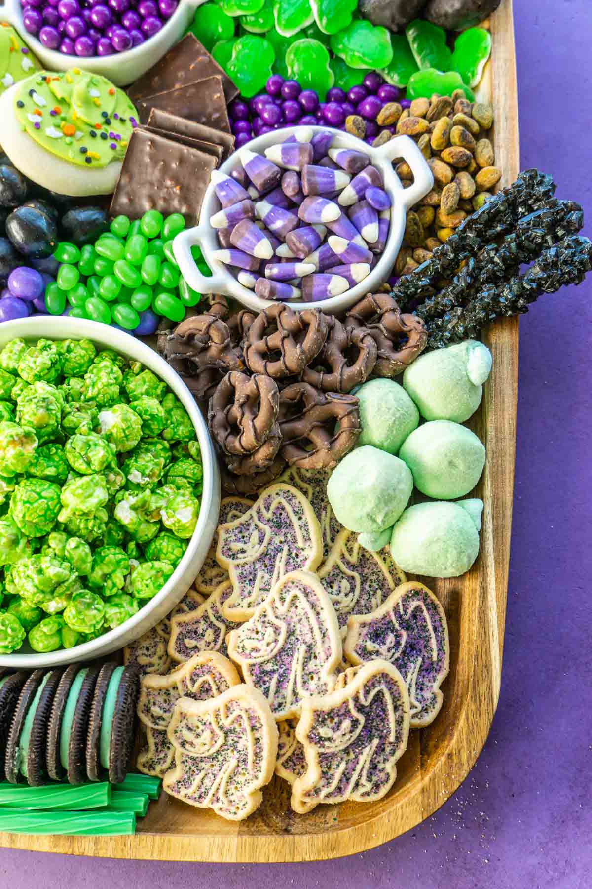 A wooden dessert board with lots of candy and cookies