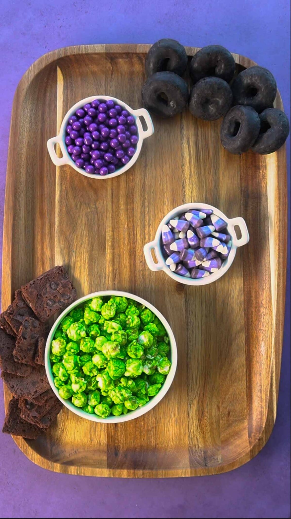 Wood board with purple candies and black donuts