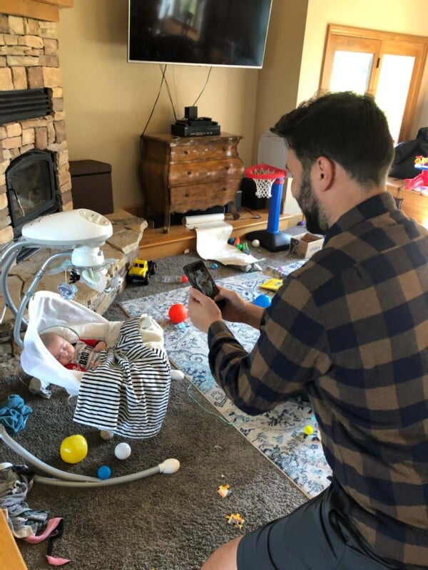 Man taking a photo on a cell phone of a sleeping child