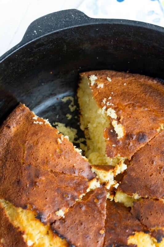 A dutch oven with cornbread and a piece cut out