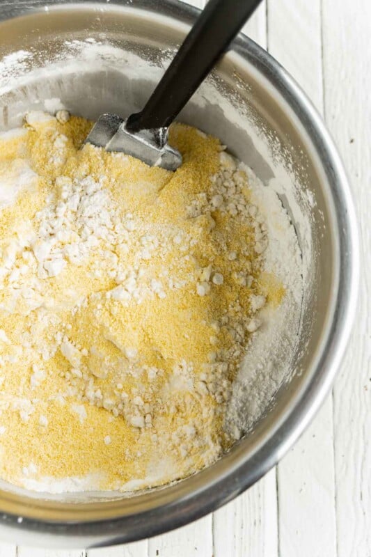 A metal bowl with cornmeal and flour in it