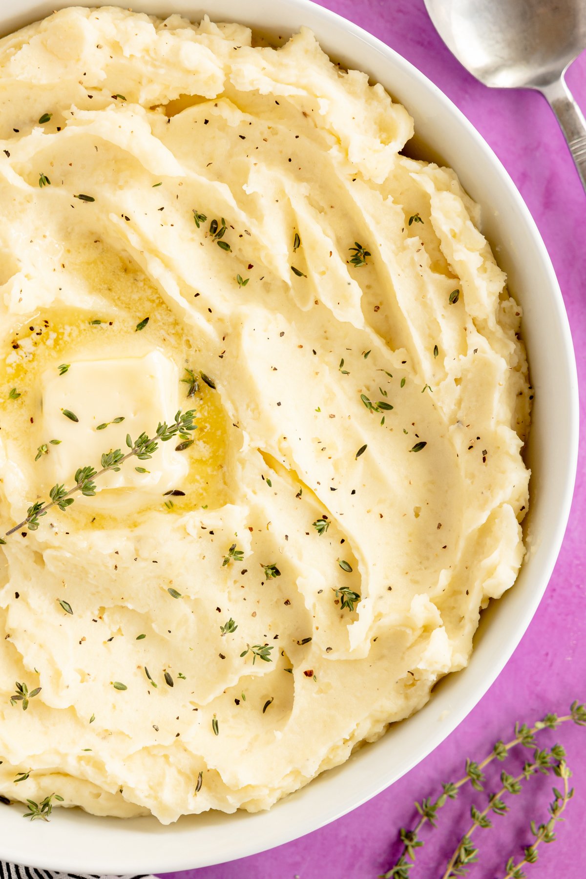 white bowl of mashed potatoes with herbs on top