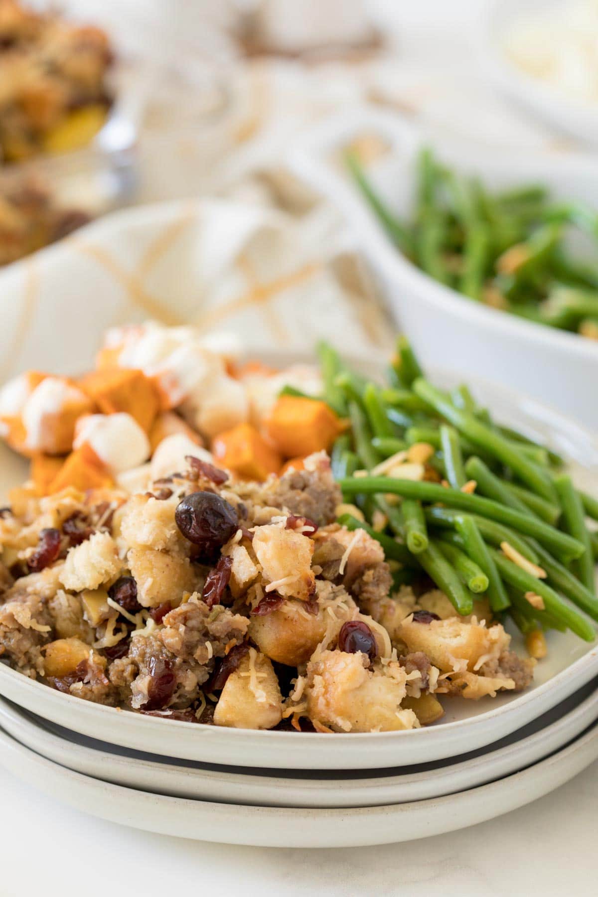 Sausage stuffing on a plate with green beans and mashed potatoes