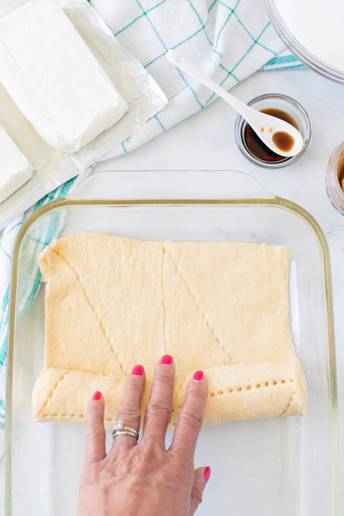 Hand rolling cresent rolls out in a glass baking dish