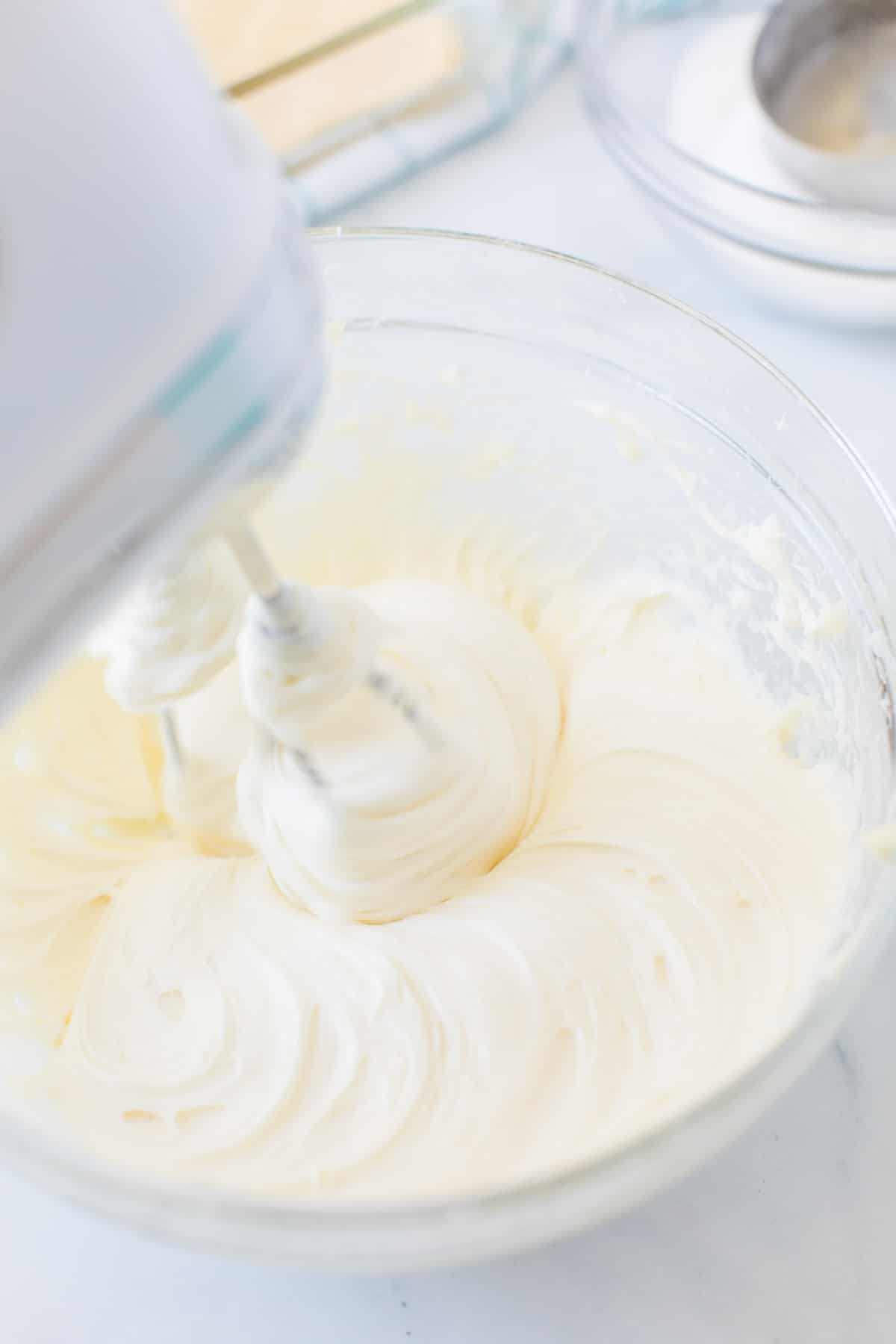 Hand mixer mixing cream cheese and sugar for sopapilla cheesecake