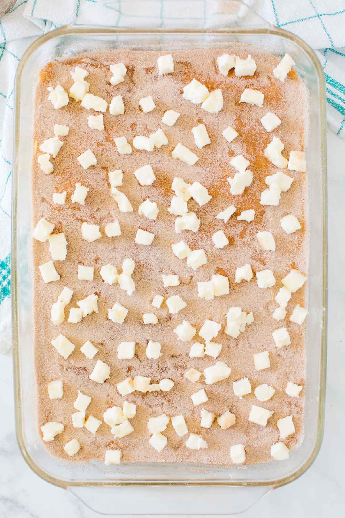 Butter dotted on top of sopapilla cheesecake in a baking dish