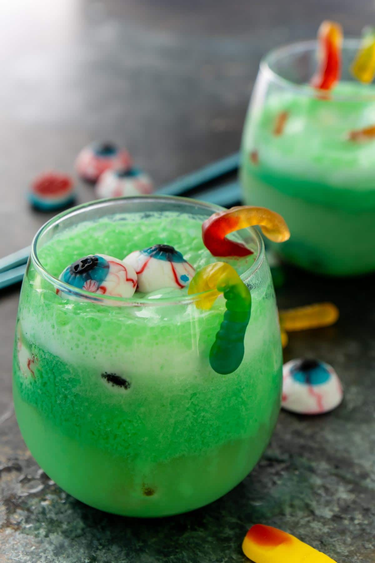 Glass of green Halloween punch with gummy worms