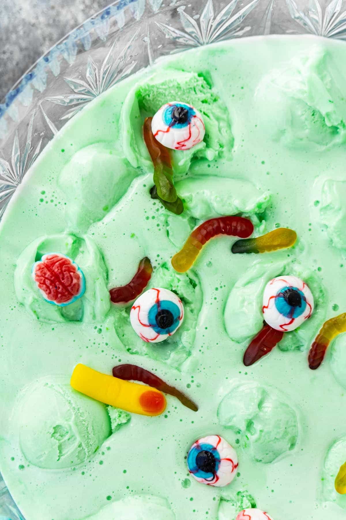 Green Halloween punch with gummy worms and eyeballs on top