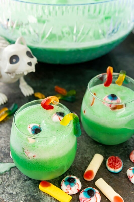 Two glasses of green Halloween punch with a zombie cat