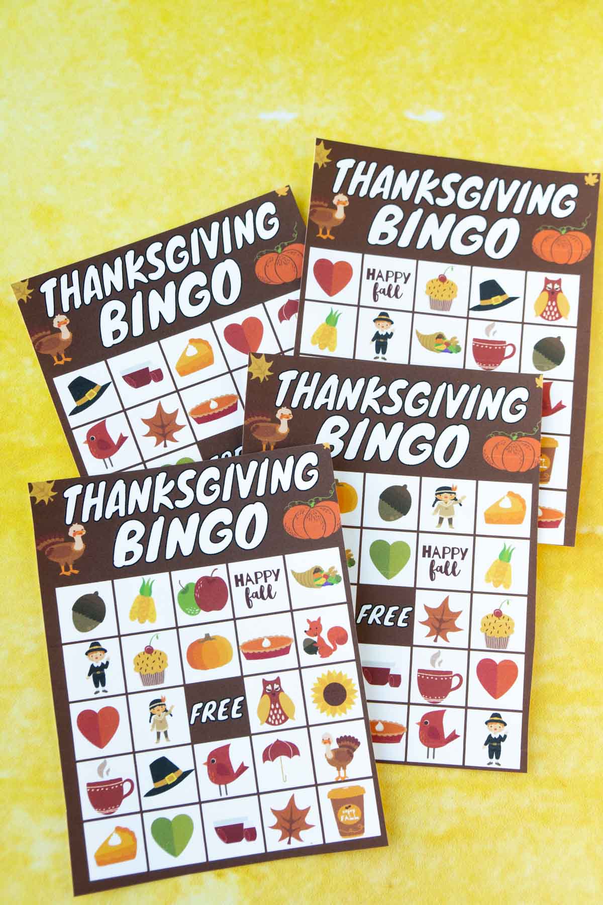 Four Thanksgiving bingo cards on a yellow background