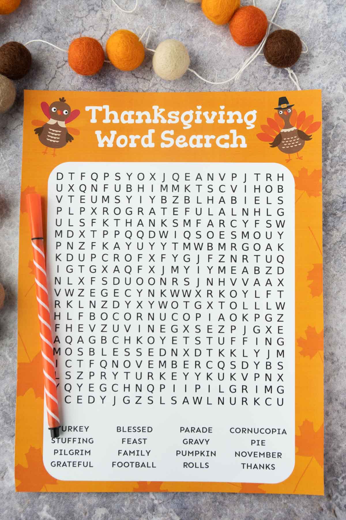 Printed out Thanksgiving word search with a pen and felt ball garland