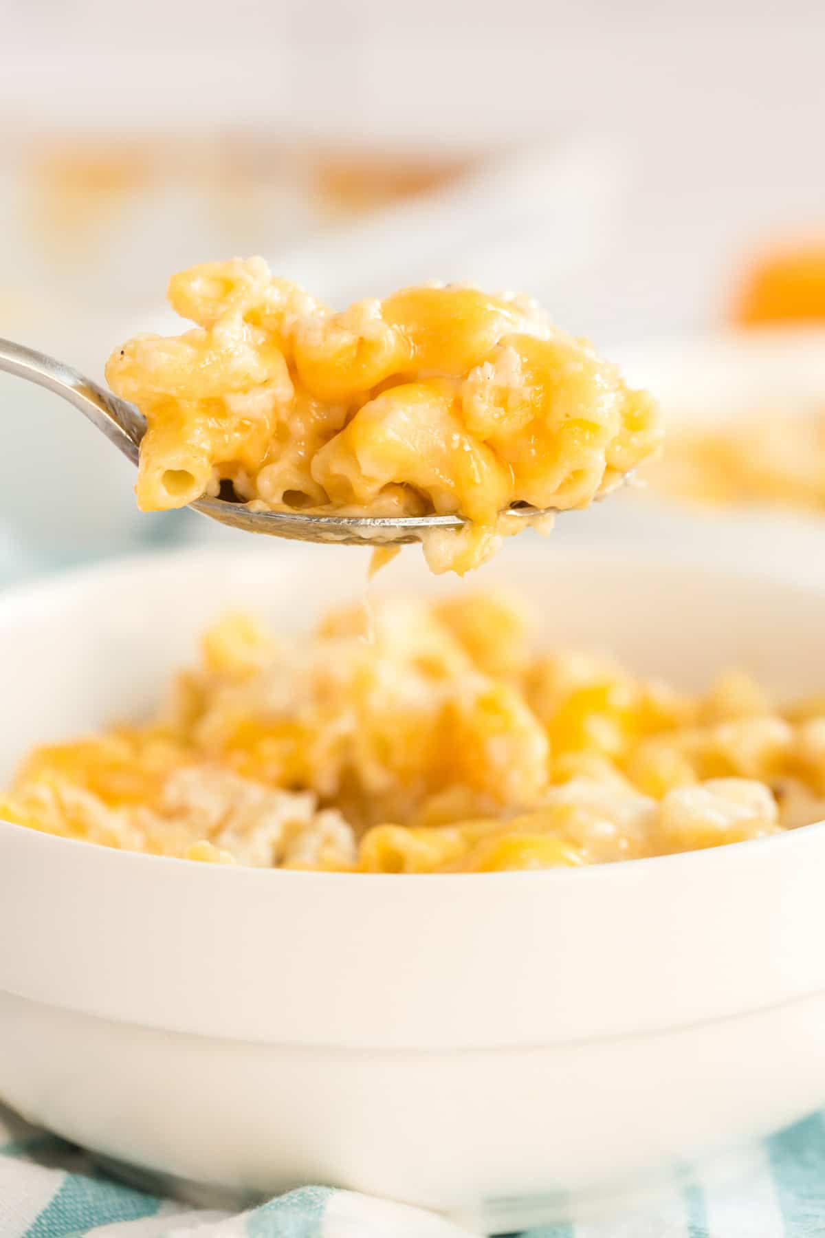 A bowl of baked macaroni and cheese with a spoon above it