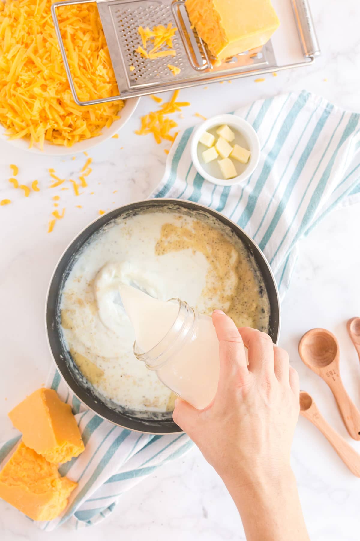 Woman's hand pouring milk into a pot with butter