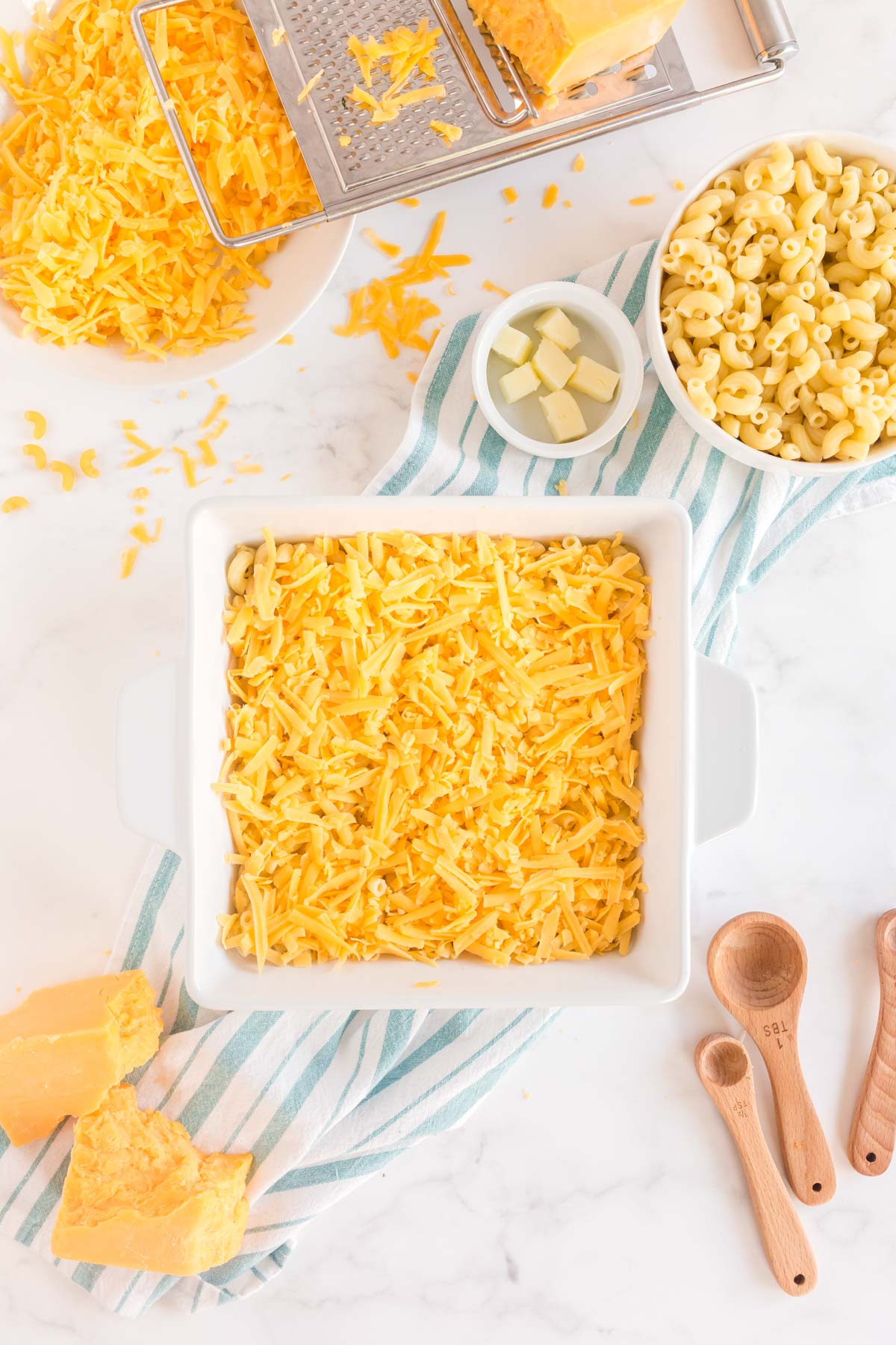 Shredded cheese on top of macaroni in a white baking dish