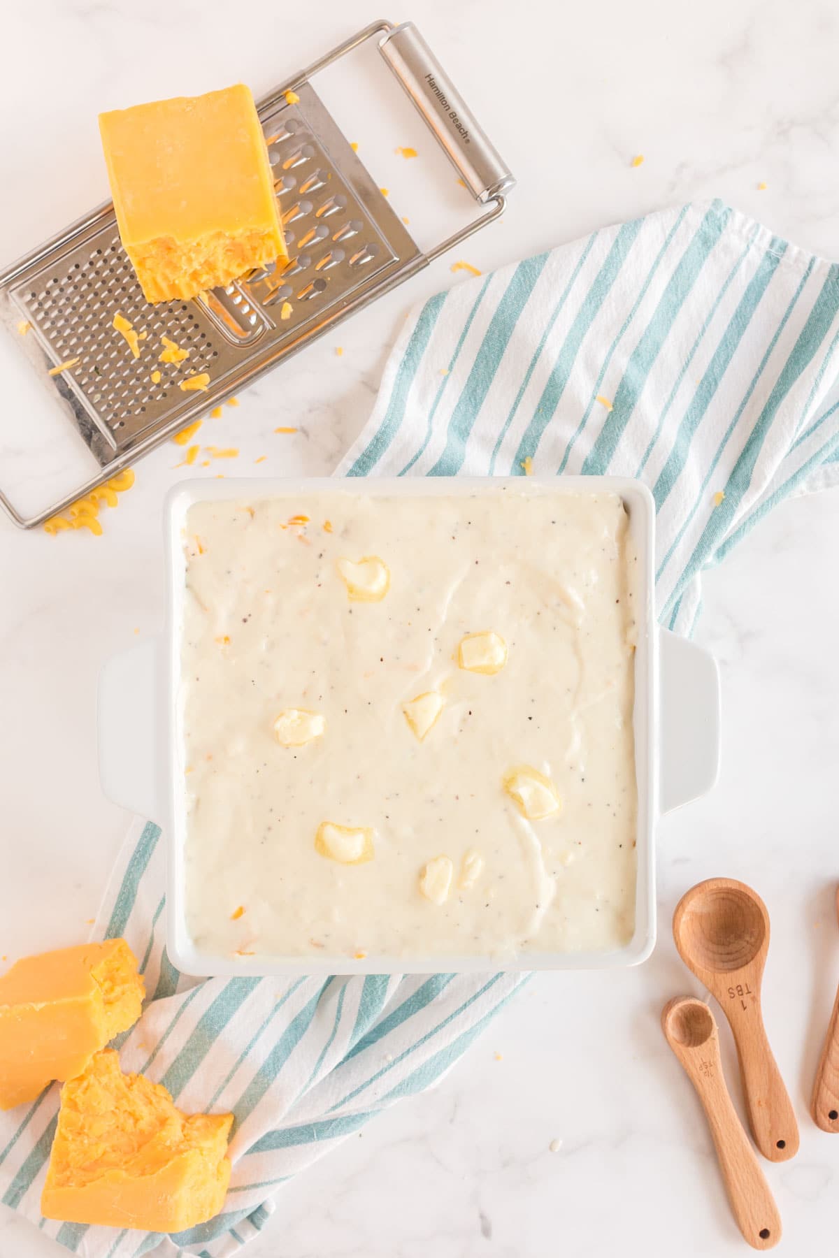 White baking dish with cubed butter and bechamel sauce