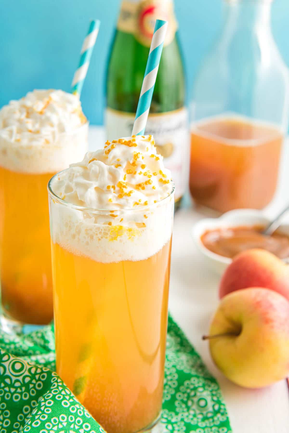 A caramel apple drink with a blue straw and whipped cream